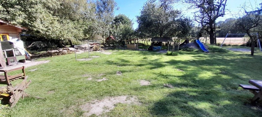 Außengelände des Zwergennest mit Spielgeräten, Sandplatz und Sitzecke